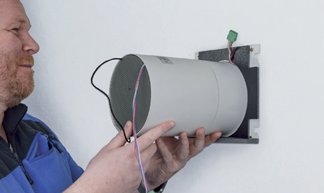 Installer fitting an AIRUNIT SOLUS 2.0 ventilation unit into an internal wall opening